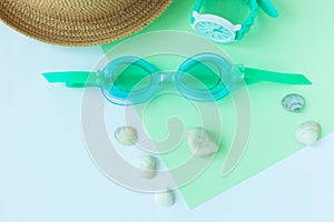Summer flatlay with watersport goggles, hat, watch on mint and light blue background, minimalistic style, copy space