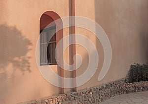 Summer floral shadows on the wall. An arch window in the wall of the arabic building.