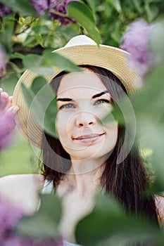 Summer floral vibes: A woman in a straw hat posing in blooming flowers in the park. Summer Portrait of young Latina