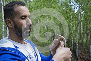 In summer  in the forest on a bright sunny day  a man holds a spindle lizard without legs in his hand