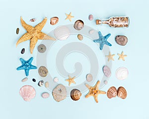 Summer frame from colorful sea stars, seashells, shellfishes, pebble stones on pastel blue with copy space.