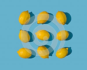 Summer frame pattern made with fresh yellow lemons on bright pastel blue background. Minimal concept on bright sunlight with sharp