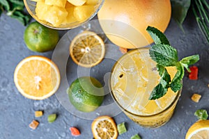 Summer fresh cold drink beverages. Ice Lemonade in the jug and lemons and orange with mint on the table outdoor. Orange lemonade