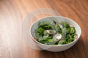 Summer fresh salad with radish, cucumber and herbs in white bowl