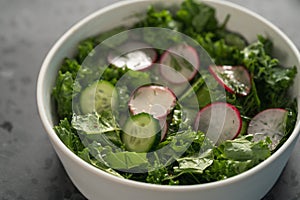 Summer fresh salad with radish, cucumber and herbs in white bowl