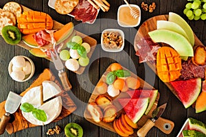 Summer fruit charcuterie table scene against a dark wood background. Overhead view.