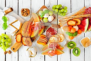 Summer fruit charcuterie table scene against a white wood background. Above view.