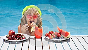 Summer fruit for children. Happy child playing in swimming pool. Kid relaxing on sea beach or pool. Summer kids vacation