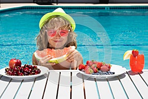 Summer fruit for children. Happy child playing in swimming pool. Portrait of summer kids. Summer kids vacation. Little