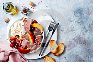 Summer fruit salad with burrata, peaches, figs, grapes and jamon or prosciutto. Top view