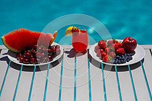 Summer fruit. Summer background. Fruit and cocktail on swimming pool background.