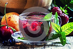 Summer fruit tea with mint in a glass cup, fresh fruit and berri