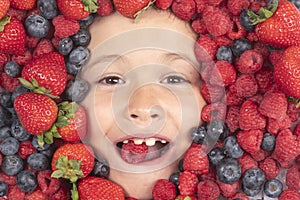 Summer fruits. Berries child face close up. Top view photo of child face with berri. Berry set near kids face. Cute