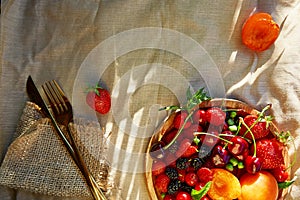 Summer fruits and berries seasonal background under hard shadows. Strawberries, apricots, cherry, raspberry with