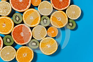 Summer fruits on blue background. Healthy food concept. Flat lay. Tropical summer mix grapefruit, orange, mandarin, kiwi, lemon