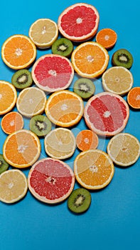 Summer fruits on blue background. Healthy food concept. Flat lay. Tropical summer mix grapefruit, orange, mandarin, kiwi, lemon