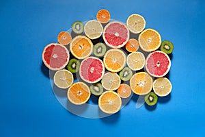 Summer fruits on blue background. Healthy food concept. Flat lay. Tropical summer mix grapefruit, orange, mandarin, kiwi, lemon