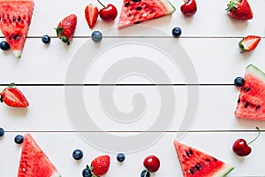 Summer fruits. Fresh juicy berries and watermelon on the white wooden table, top view