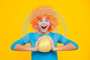 Summer fruits. Teenager child girl hold citrus fruit pummelo or pomelo, isolated on yellow background. Kid healthy