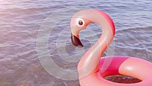 Summer fun beach. Pink inflatable flamingo in blue sea water on summer ocean beach background. Funny bird toy for kids