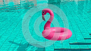 Summer fun beach. Pink inflatable flamingo in pool water for summer beach background. Funny bird toy for kids