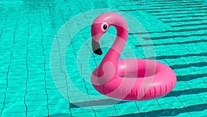 Summer fun beach. Pink inflatable flamingo in pool water for summer beach background. Funny bird toy for kids