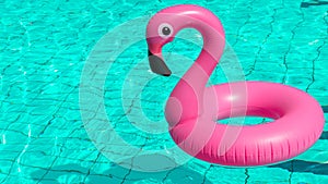 Summer fun beach. Pink inflatable flamingo in pool water for summer beach background. Funny bird toy for kids.