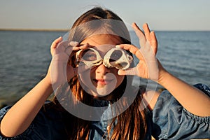 Summer fun concept with portrait of a girl with shells on a beach