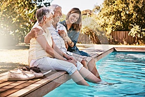 Summer fun for the family. a happy young woman spending quality time with her elderly parents at the pool.