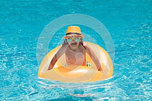 Summer fun kids face. Child boy in swim pool swimming on inflatable ring. Kid swim with orange float. Water toy, healthy