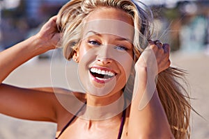 Summer fun. Portrait of an attractive young blonde woman in a bikini laughing while at the beach.