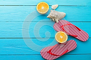 Summer fun time and flip flops. Sea shell. Slippers and orange fruit on blue wooden background. Mock up and picturesque. Top view.