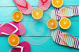 Summer fun time and flip flops. Slippers and orange fruit on blue wooden background. Mock up and picturesque. Top view. Copy space