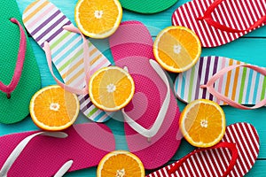 Summer fun time and flip flops. Slippers and orange fruit on blue wooden background. Mock up and picturesque. Top view. Sandals