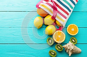 Summer fun time and fruits on blue wooden background. Mock up and picturesque. Orange, lemon, kiwi fruit in bag and shell