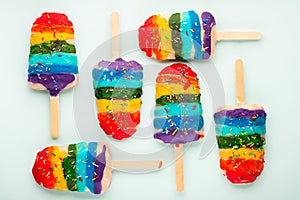 summer funny creative concept of popsicles or lollipops with sprinkles and icing rainbow colors over background