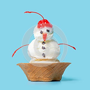 summer funny creative concept of scoops with snowman ice cream in waffle cup isolated on blue background