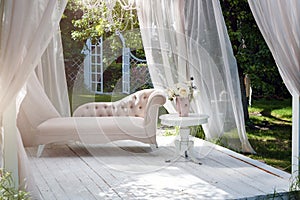 Summer garden gazebo with curtains and sofa for relaxation.