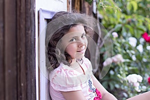 Summer.garden.girl with dark hair sitting on the doorstep on a background of flowers