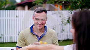 Summer, in the garden. A man, father, having fun with his family outdoors, twisting, applying mandarins to his eyes