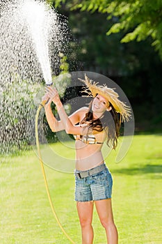 Summer garden woman play with water hose