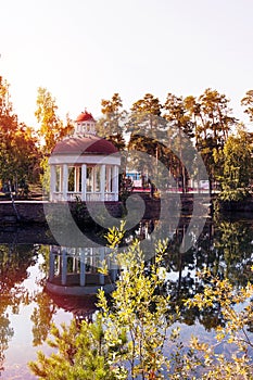 Summer gazebo by the lake at sunset