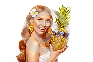 Summer girl Bright woman with a pineapple in her hands with earrings in the form of a tropical leaf, with sun glasses on a white