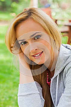 Summer girl portrait. Caucasian blonde woman smiling happy on sunny summer or spring day outside in park.