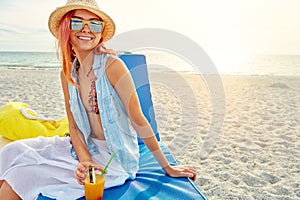 Summer gives me that good feeling. an attractive young woman lounging on the beach and enjoying a cocktail.