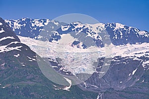 In summer, the glacier is flanked by dark, rocky mountains.