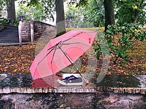 Summer gone and forgot sneakers in city park under umbrella rainy day Autumn season come change weather background