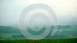 Summer green hills and field with low clouds timelapse