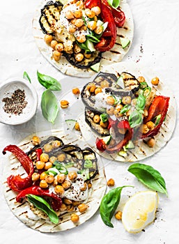 Summer grilled garden vegetables and spicy chickpeas vegetarian tortillas on a light background, top view. Healthy food picnic