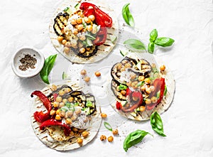 Summer grilled garden vegetables and spicy chickpeas vegetarian tortillas on a light background, top view. Healthy food